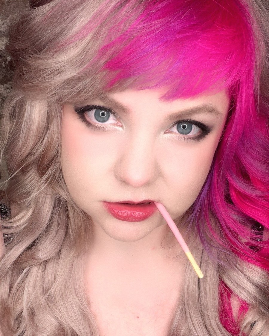 Michelle, the creator of Ferality: blonde hair with a bright pink streak, looking into the camera.